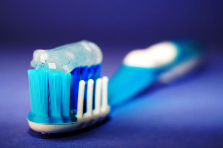 A toothbrush with toothpaste on the bristles where the head of the toothbrush is in focus