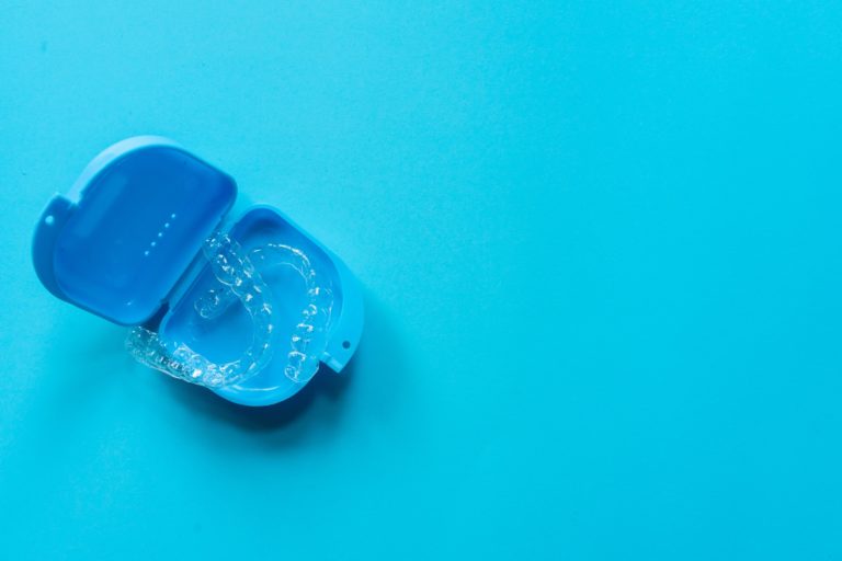 Invisalign/clear aligners sitting in a blue protective container on a blue background