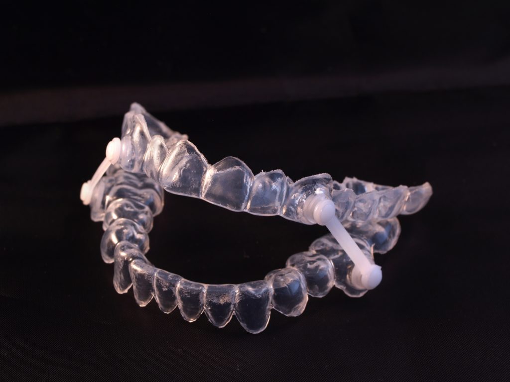 Clear Custom Sleep Apnea Device on black background from Capital Dental Lincoln Nebraska
