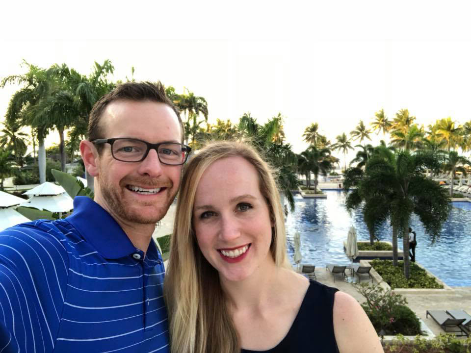 Dr. Killeen and his wife outside with a pool and palm trees in the background