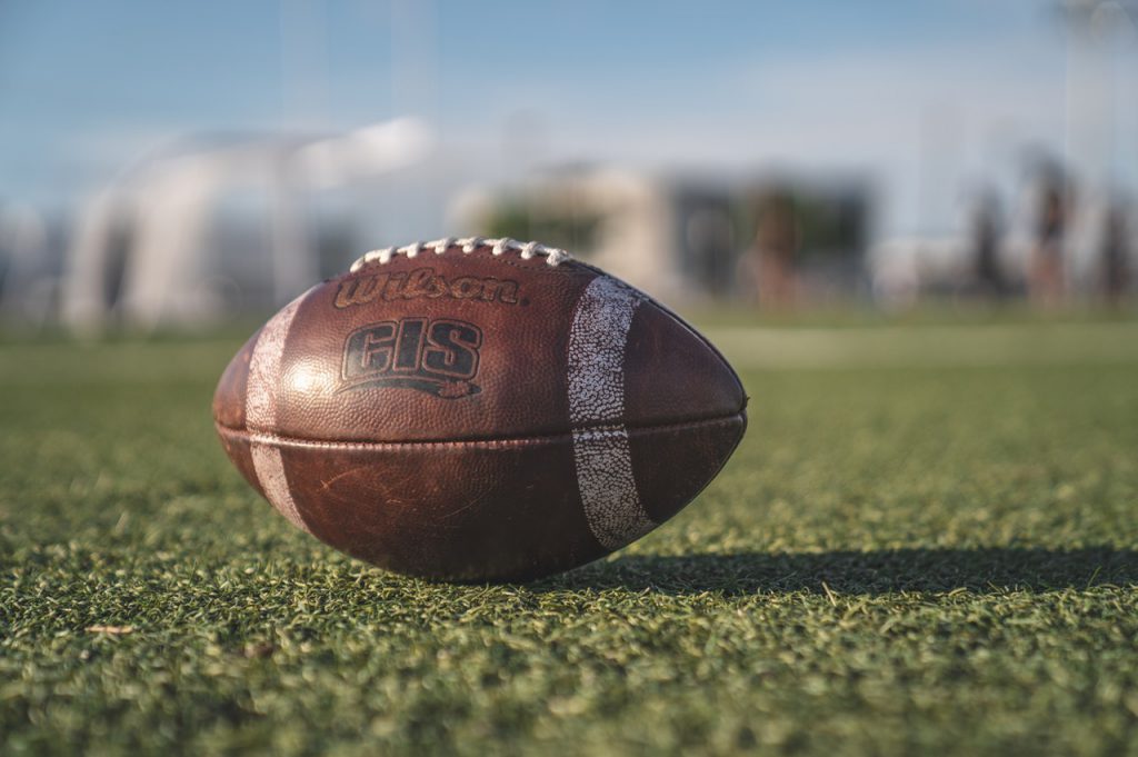 Closeup of a brown Wilson football on a green turf football field