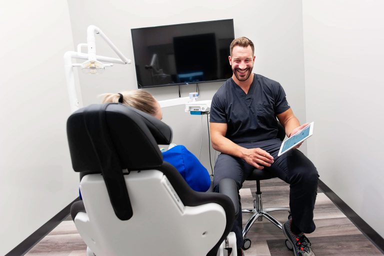 Dr. Brandon Chapek of Capital Dental discussing dental progress and needs with a patient