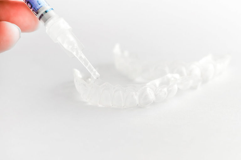 Opalescence teeth whitening agent being placed in a dental tray